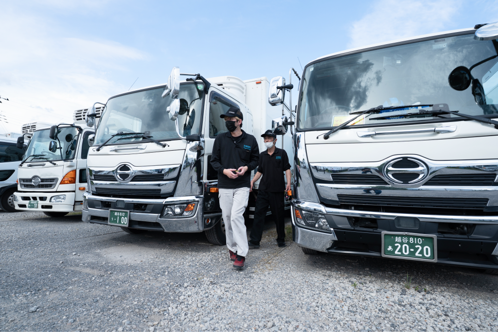 営業所に並ぶ配送車両とスタッフ